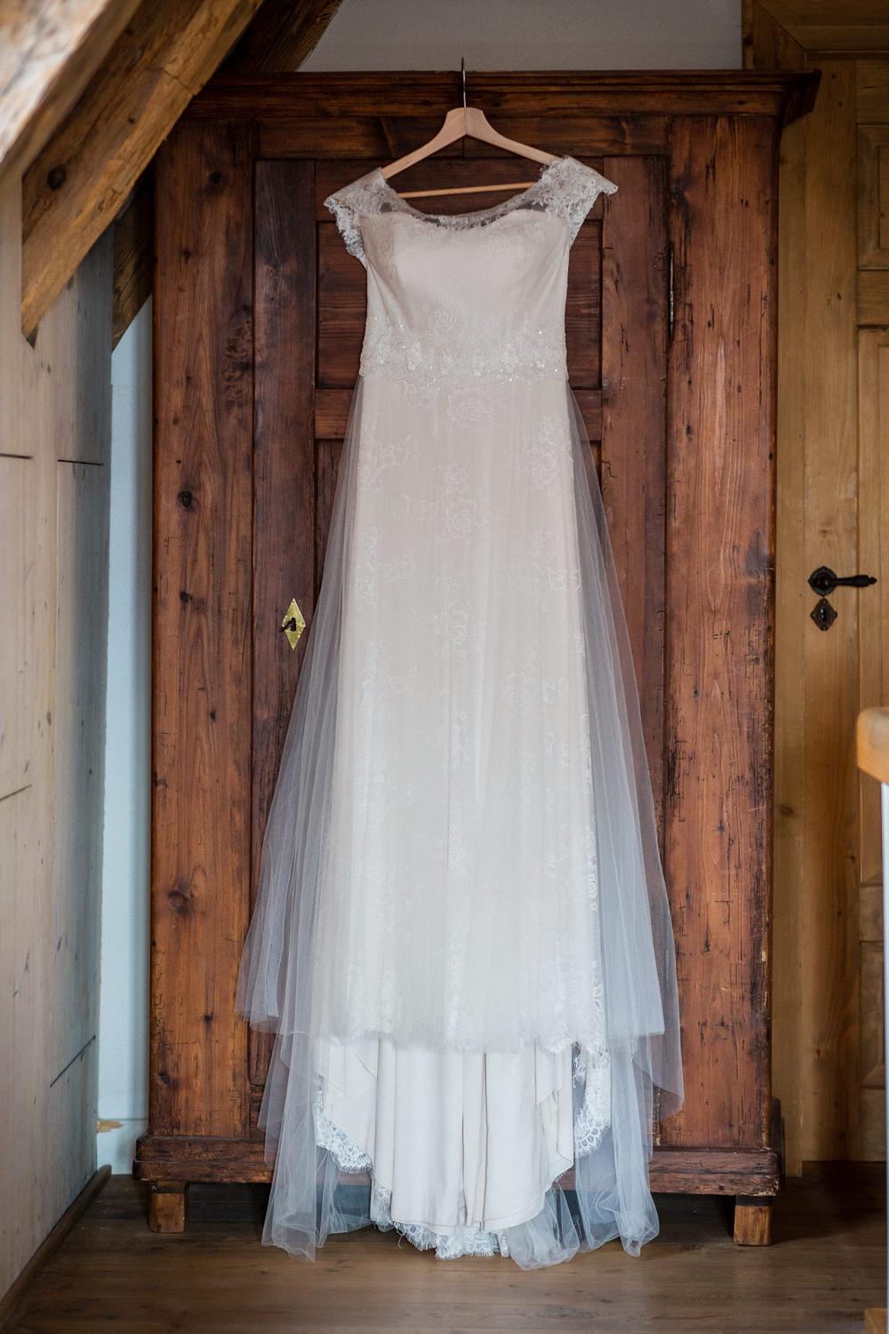 Brautkleid hängt vor rustikalem Holzschrank im Getting Ready Zimmer