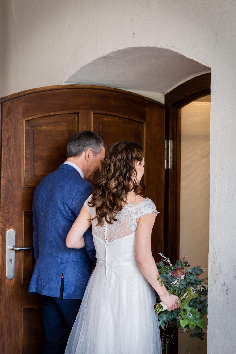 Braut tritt mit ihrem Vater durch das Portal zur Trauung
