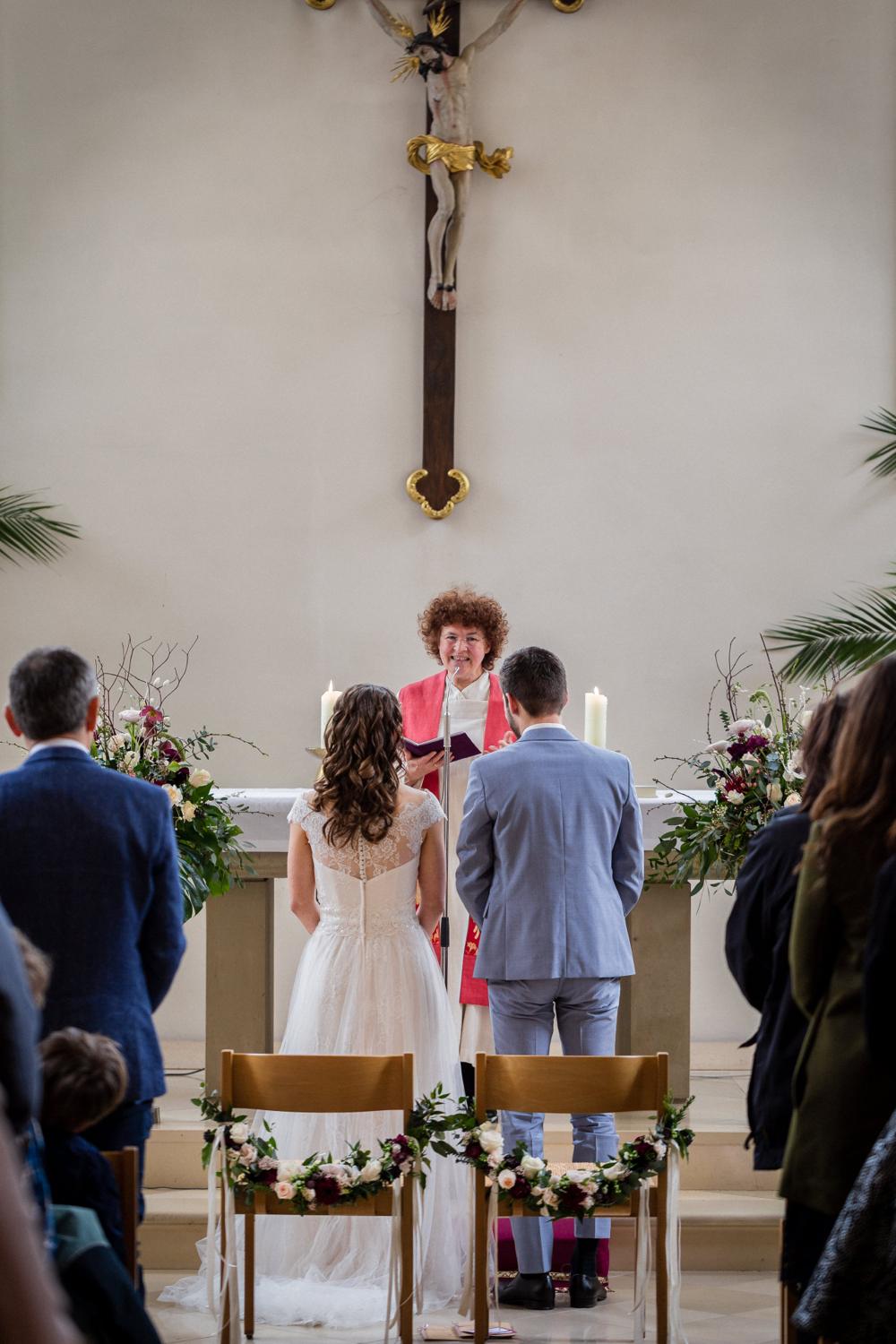 Pfarrerin spricht am Altar zum Brautpaar unter dem Kruzifix