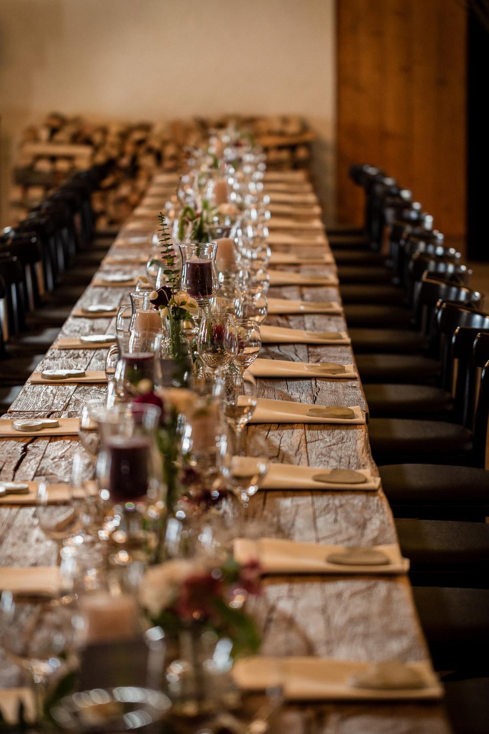 Lange Holztafel mit Kerzen und Weingläsern für die Hochzeitsfeier