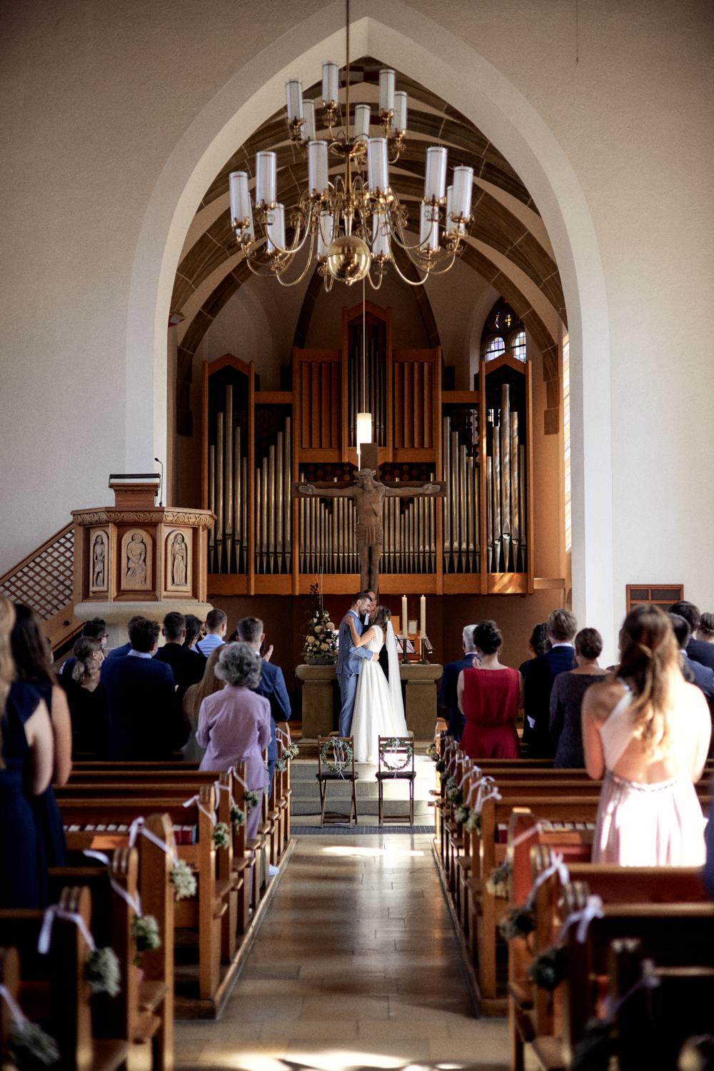Brautpaar steht eng umschlungen vor Altar und Orgel