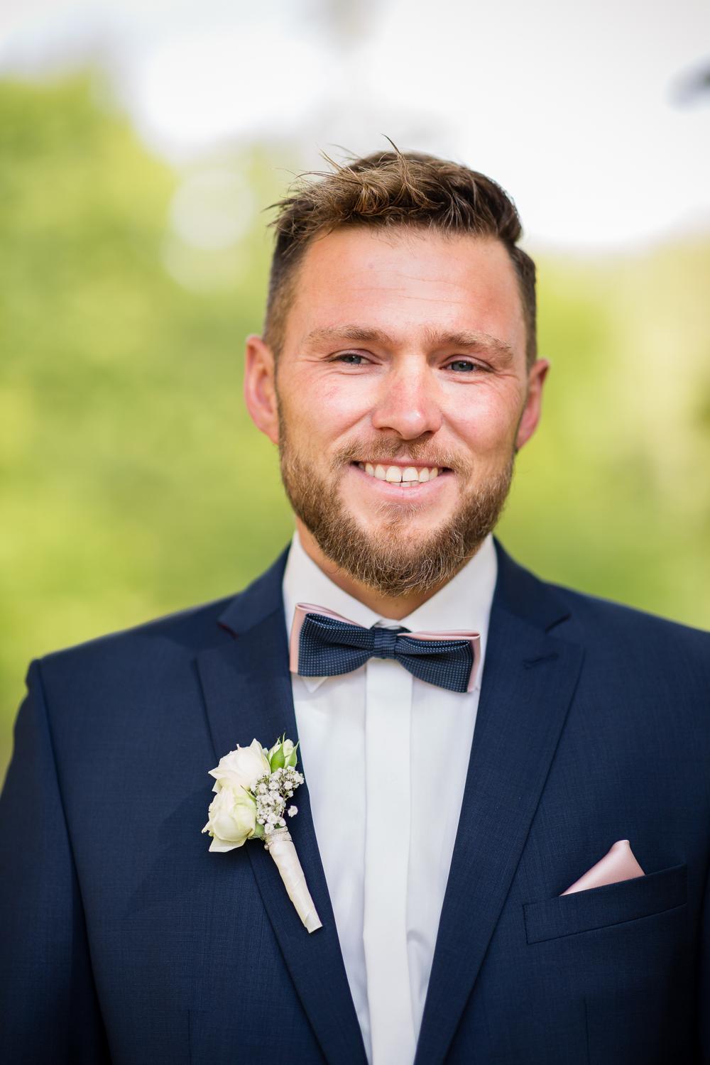 Portrait des lächelnden Bräutigams im Klostergarten Kirchberg, Fliege und Ansteckblume