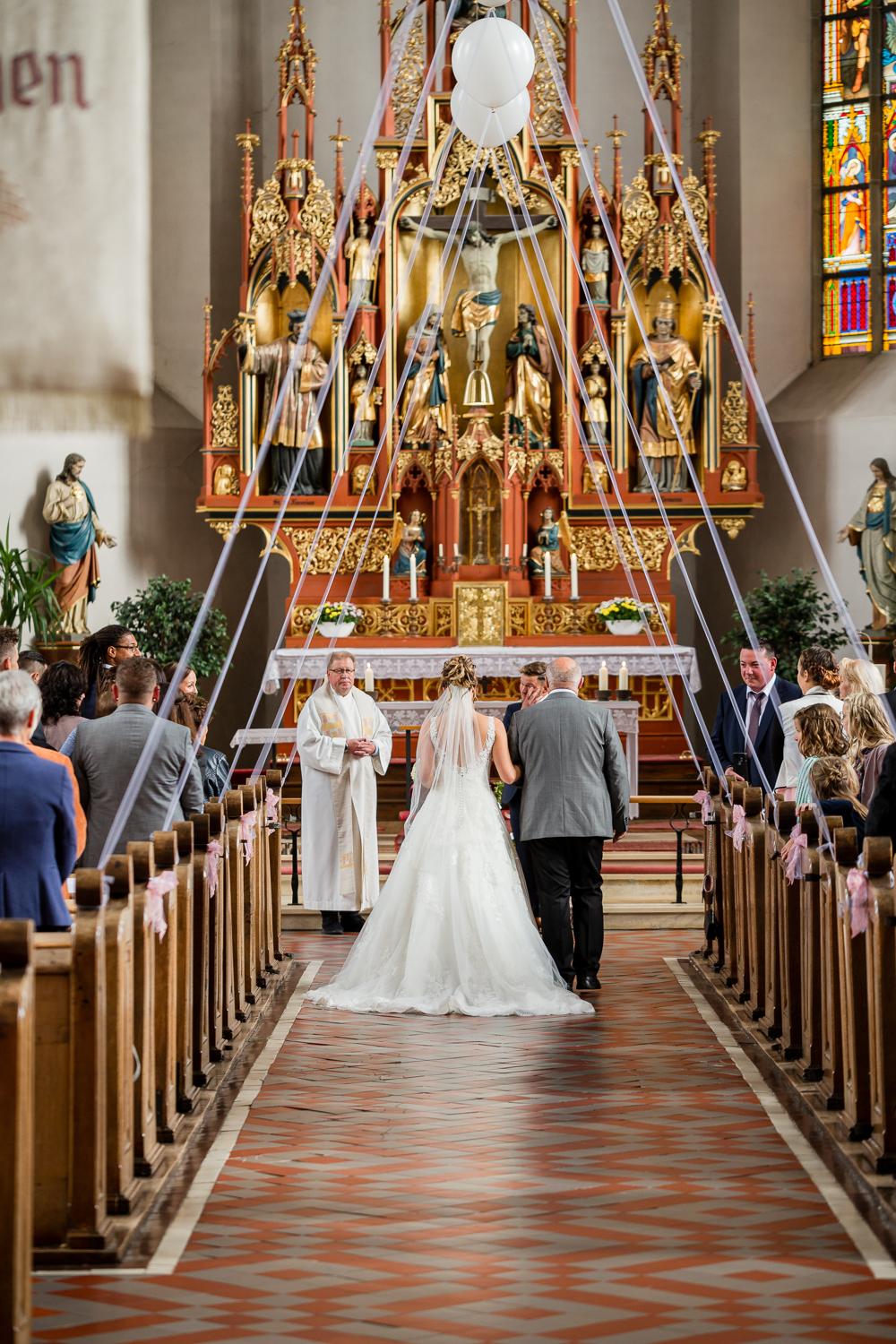 Totale: Braut schreitet zum Altar der St. Clemenskirche Gruol mit gotischem Hochaltar