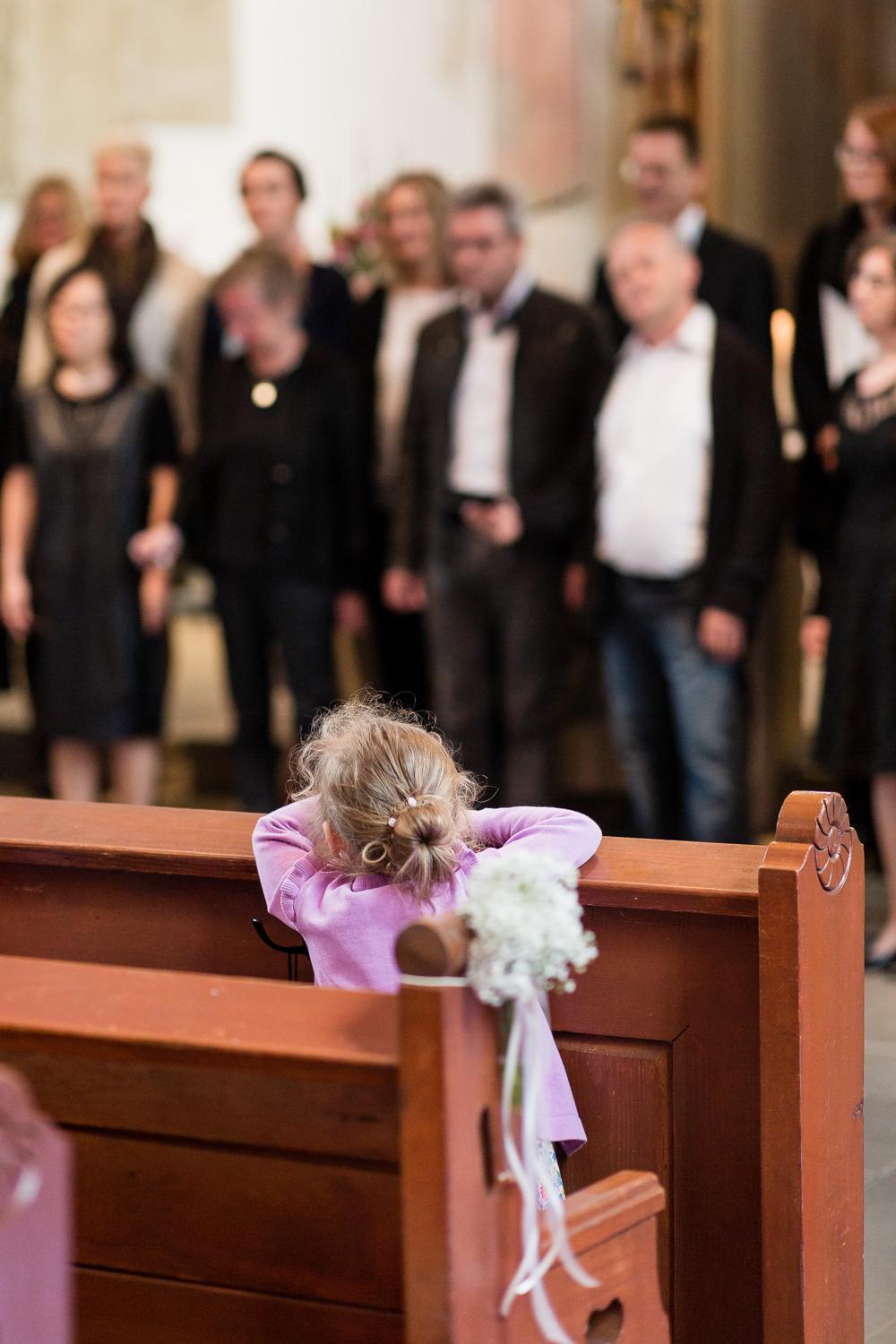 Kleines Mädchen schaut über die Kirchenbank während der Trauung in Gärtringen