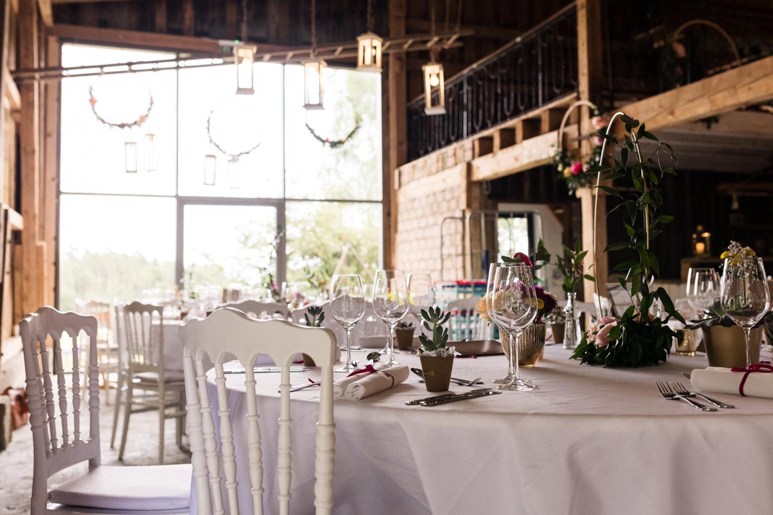 Nahaufnahme eines gedeckten Hochzeitstisches mit Weingläsern und Blumenschmuck am Lindenhof