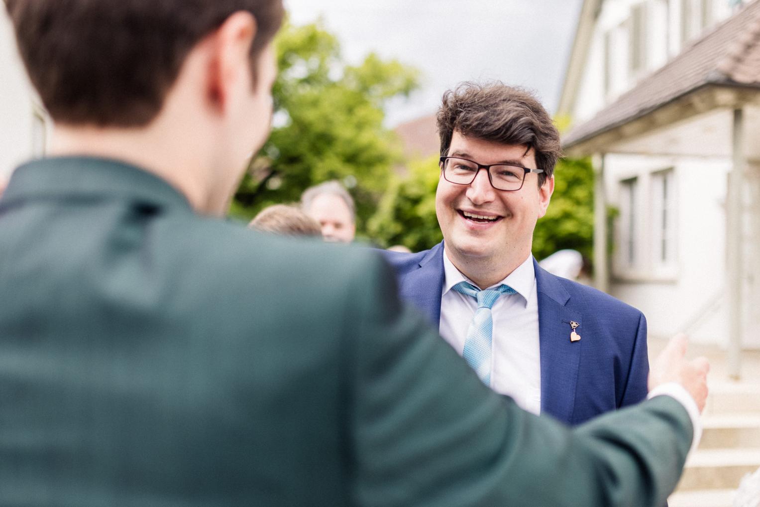 Bräutigam und Gast begrüßen sich herzlich beim Empfang vor der Kirche Mötzingen