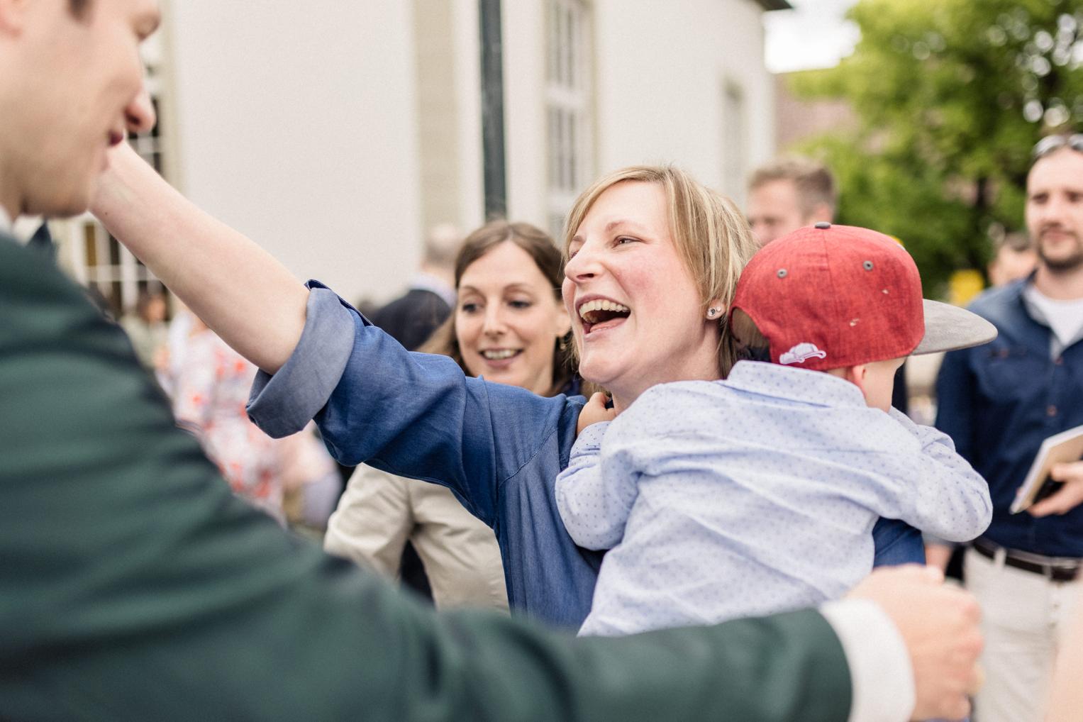 Fröhliche Gästin mit Kind auf dem Arm beim Empfang nach der Trauung an der Kirche Mötzingen
