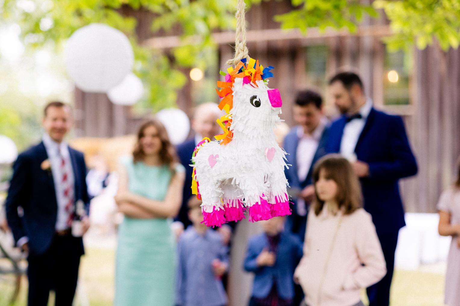 Einhorn-Piñata hängt an einem Baum beim fröhlichen Hochzeitsfest im Garten des Lindenhof Mötzingen