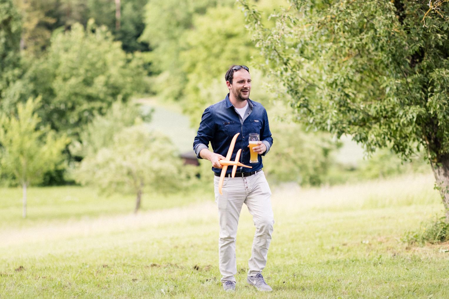 Gast wirft lachend einen Bumerang auf der Wiese beim Hochzeitsfest am Lindenhof Mötzingen