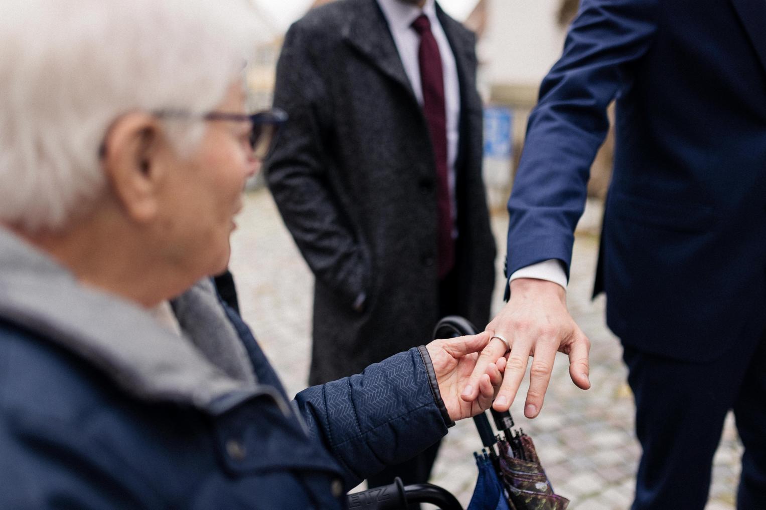 Bräutigam zeigt nach der Trauung seinen Ehering einer älteren Person während des Gratulierens in Herrenberg.