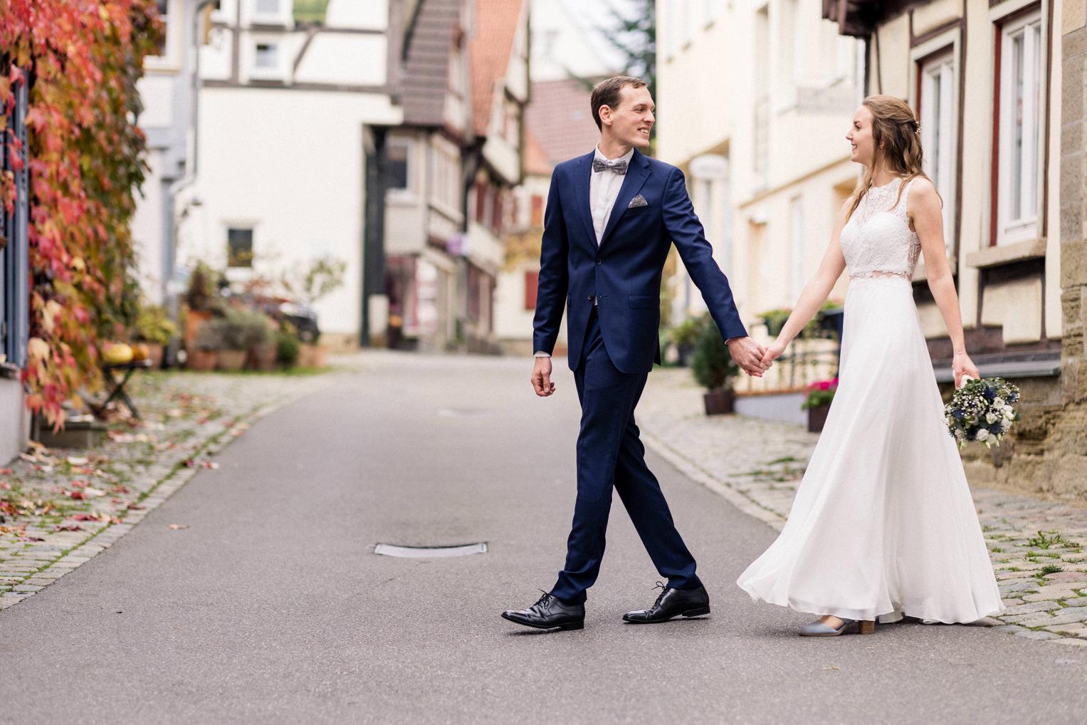 Brautpaar spaziert Hand in Hand durch die historische Altstadt von Herrenberg im Herbst.