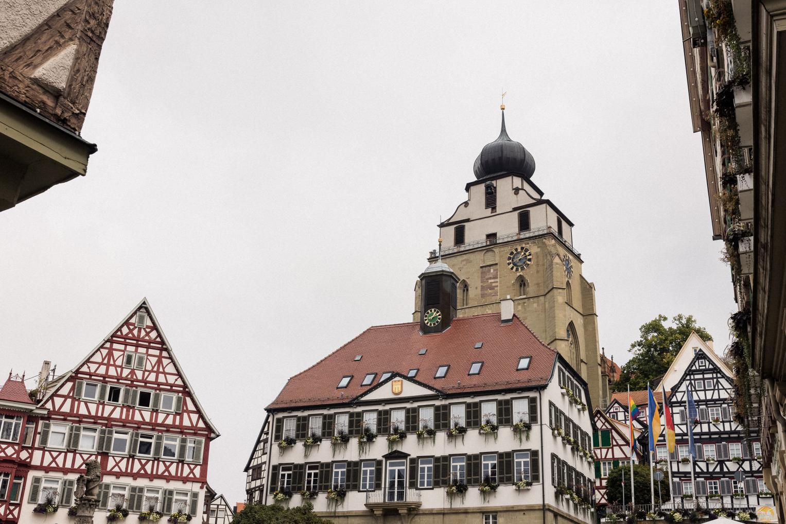 Außenansicht der Stiftskirche in Herrenberg, umgeben von historischen Fachwerkhäusern.