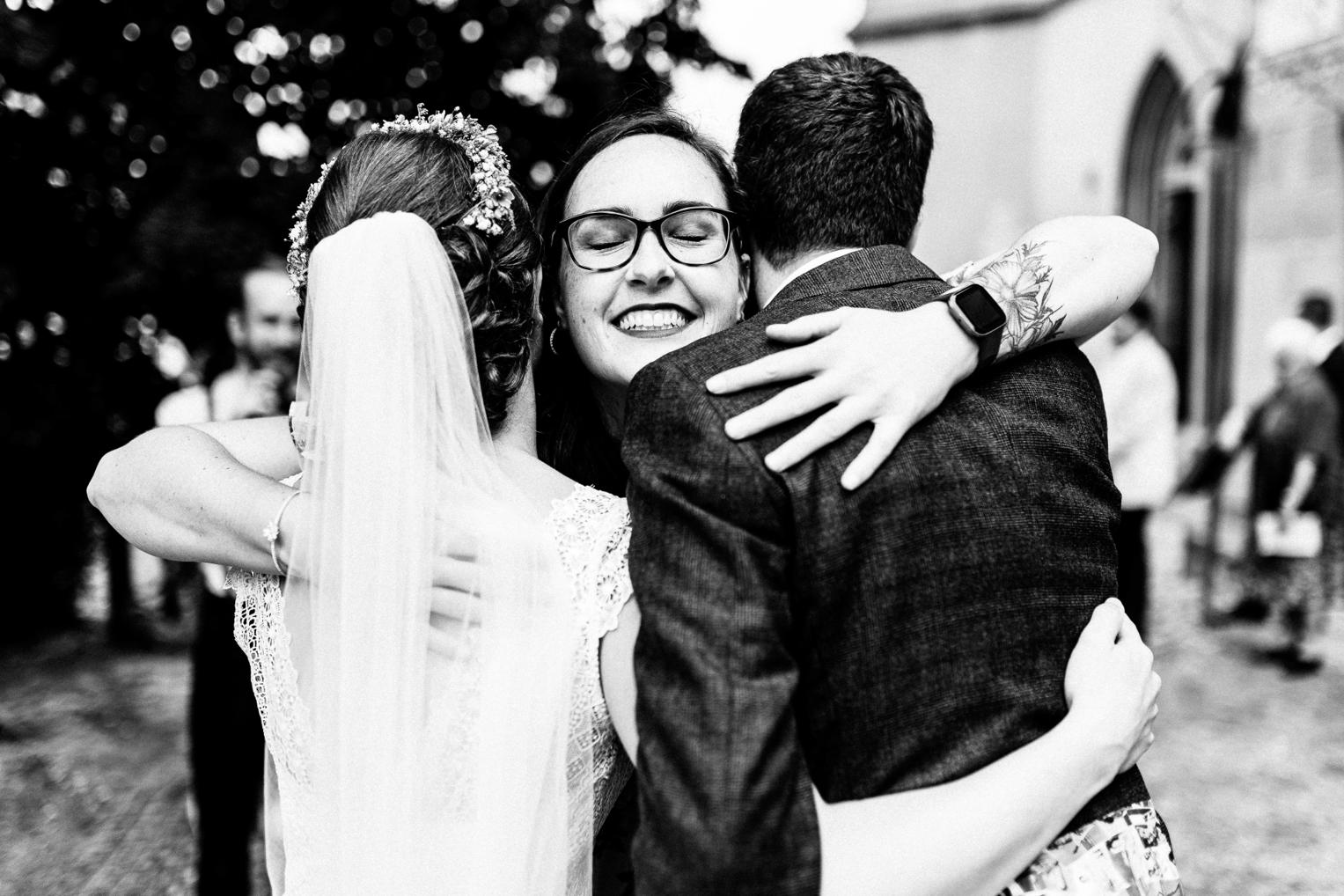 Braut wird vor der Stiftskirche Herrenberg herzlich von einer jungen Frau umarmt, beide lachen glücklich.