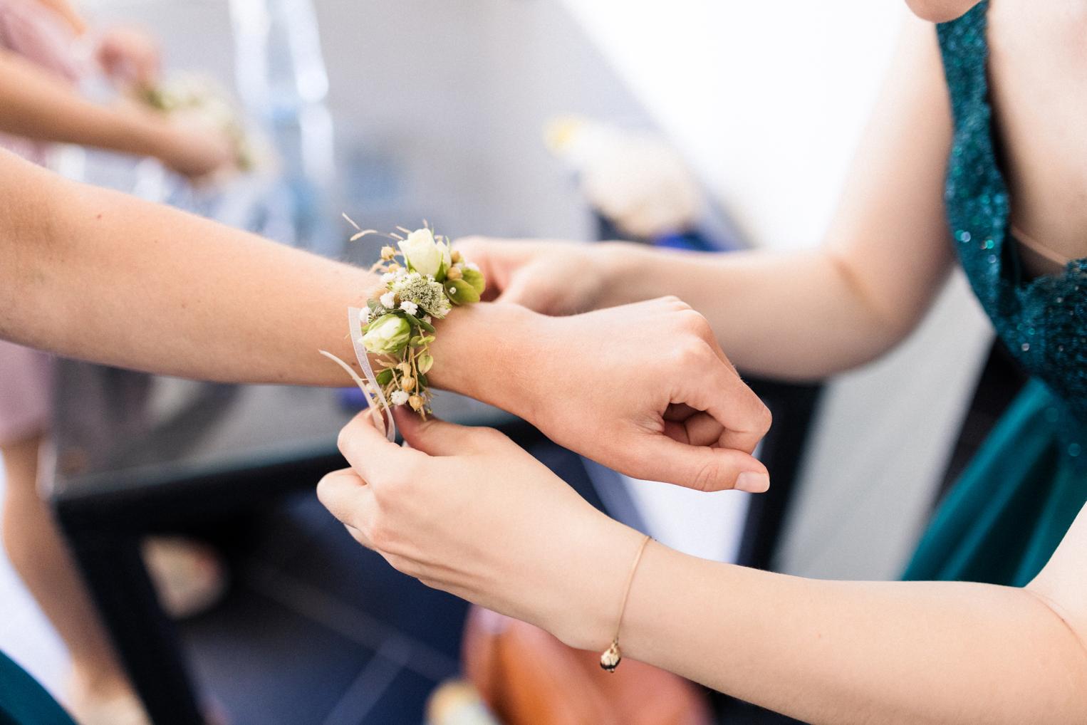 Blumenarmband mit weißen Blüten wird der Brautjungfer am Handgelenk befestigt