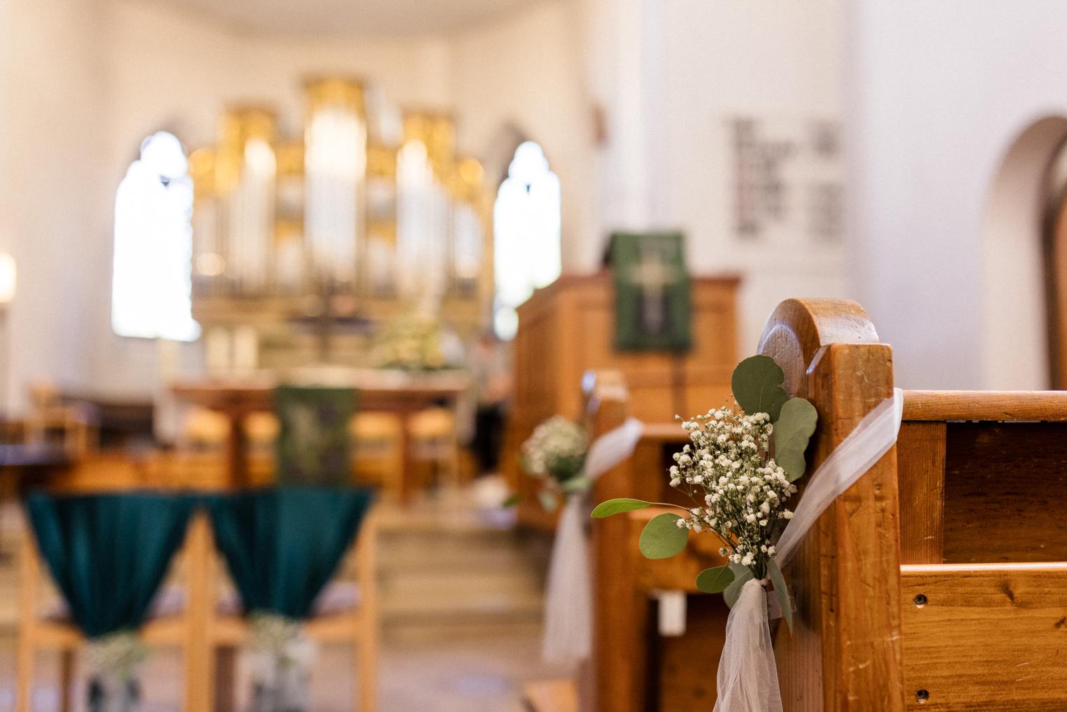 Kirchenbank mit Eukalyptus und Schleierkraut dekoriert, Orgel unschärfer im Hintergrund