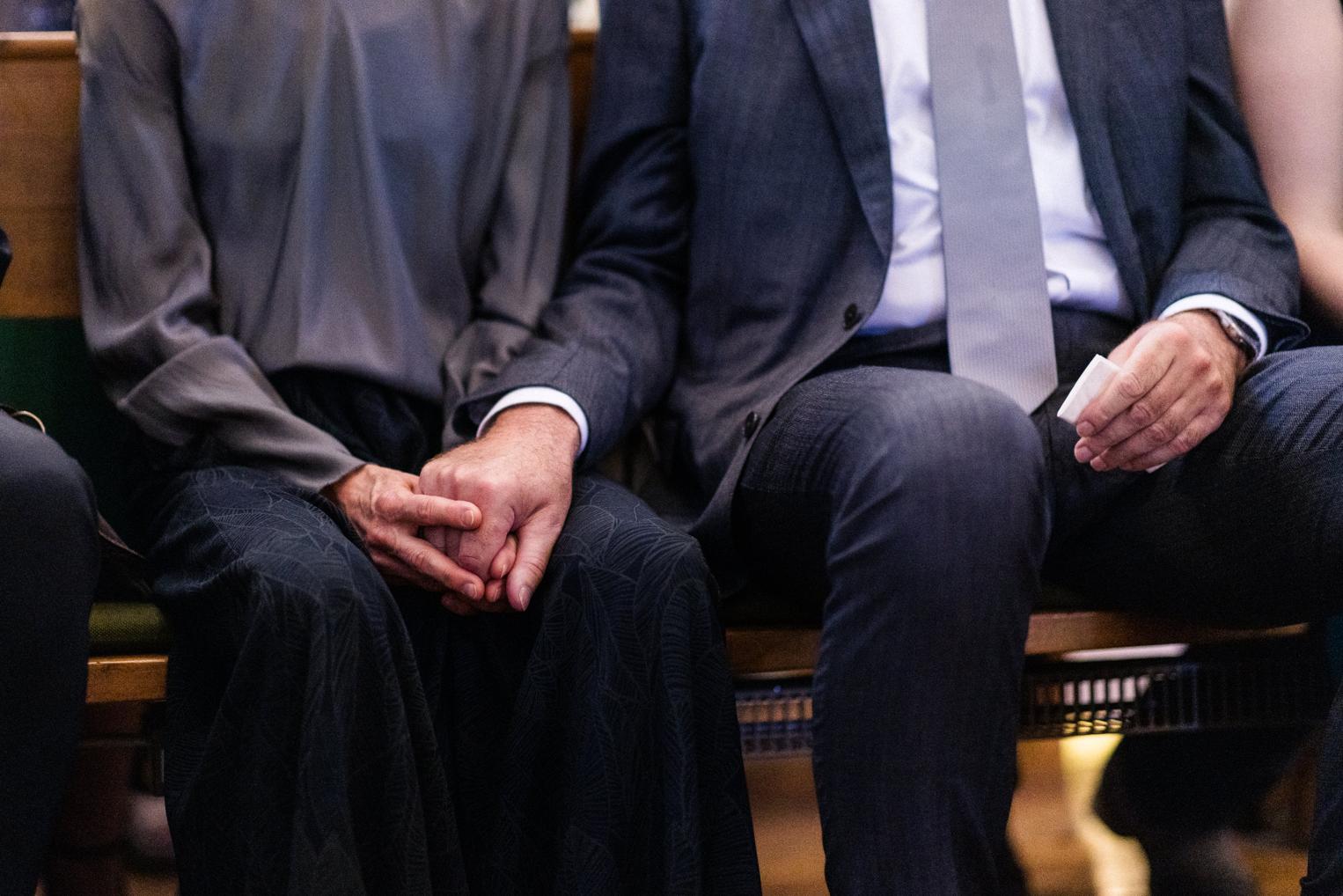 Gefaltete Hände der Gäste in der Kirchenbank während der Trauung, Detail