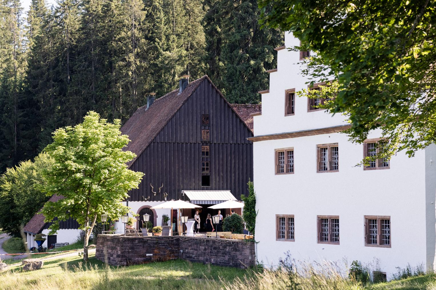 Hofgut Bärenschlössle bei Freudenstadt – Fachwerk und Staffelgiebel vor Schwarzwaldtannen, Gäste auf der Terrasse