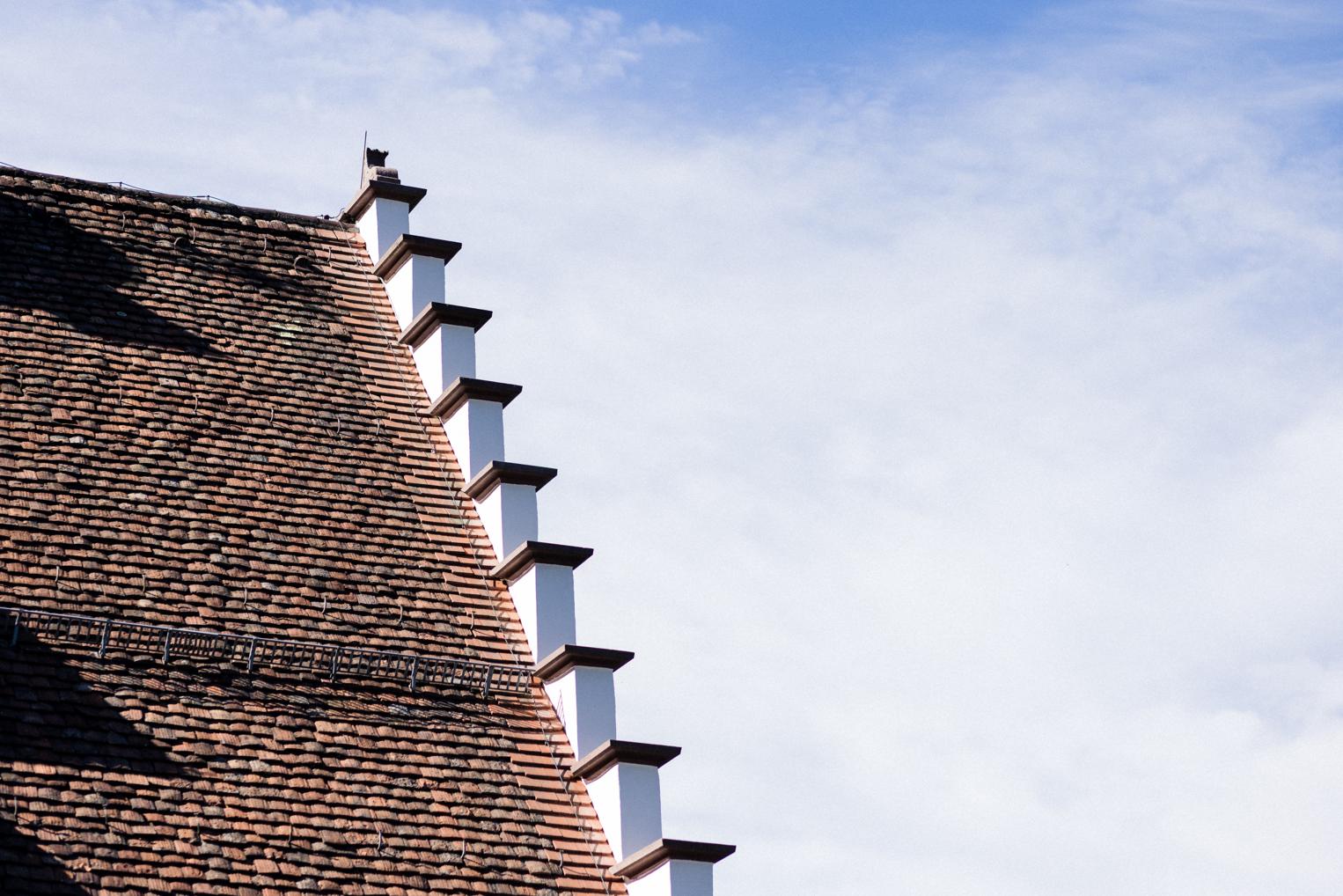 Treppengiebel des Bärenschlössle mit alten Dachziegeln vor blauem Himmel, Detail