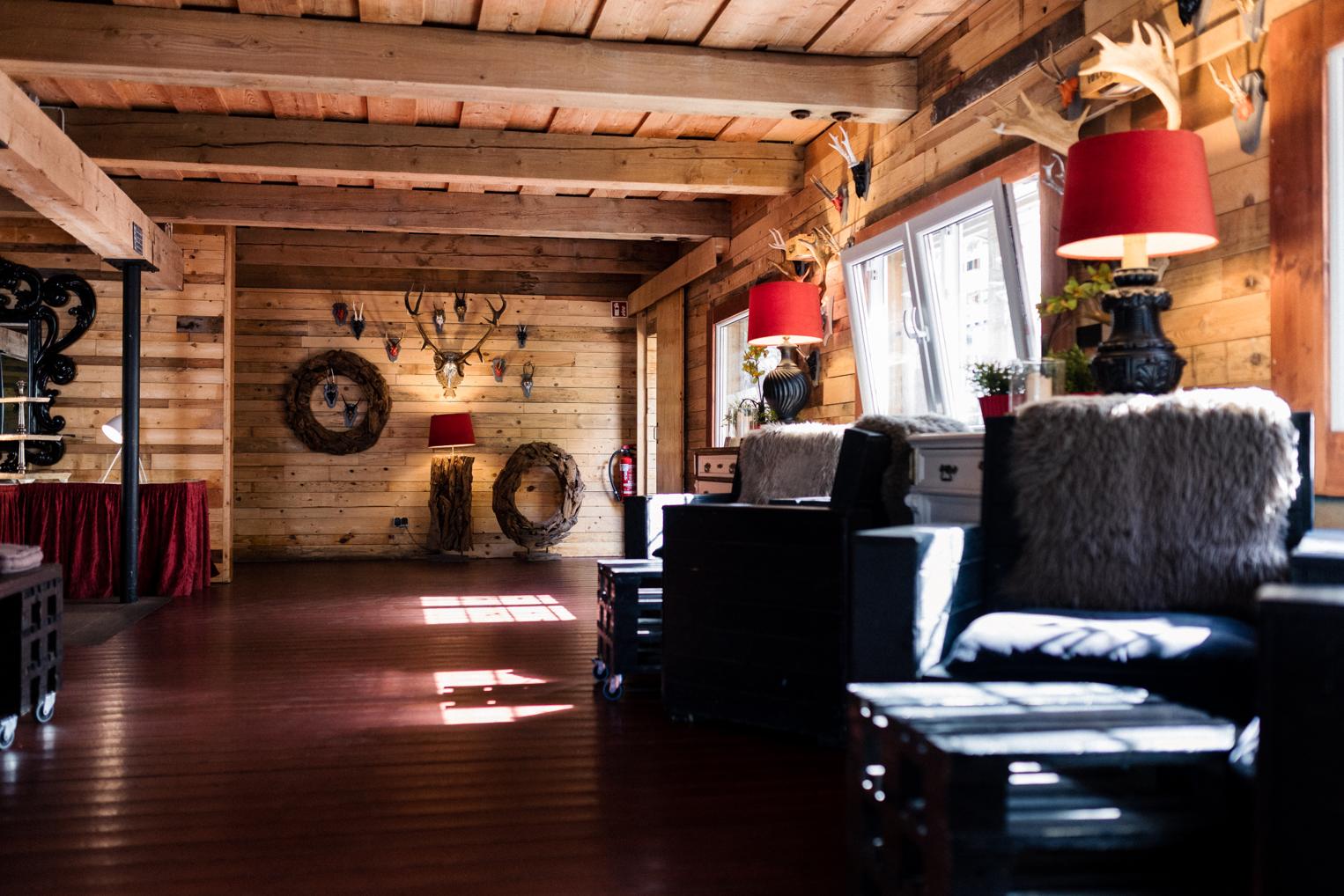 Lounge im Bärenschlössle mit Ledersesseln, Fellen, roten Lampenschirmen und Holzwänden
