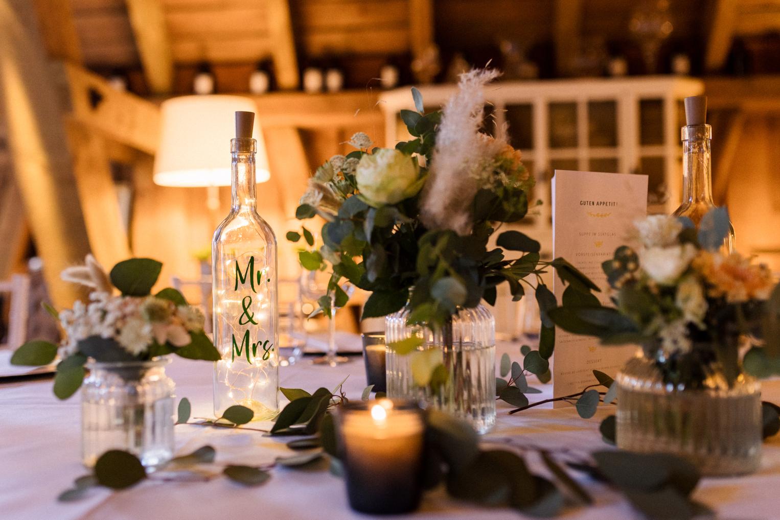Tischdeko mit Mr & Mrs Lichtflasche, Eukalyptus und Blumen im Festsaal des Bärenschlössle