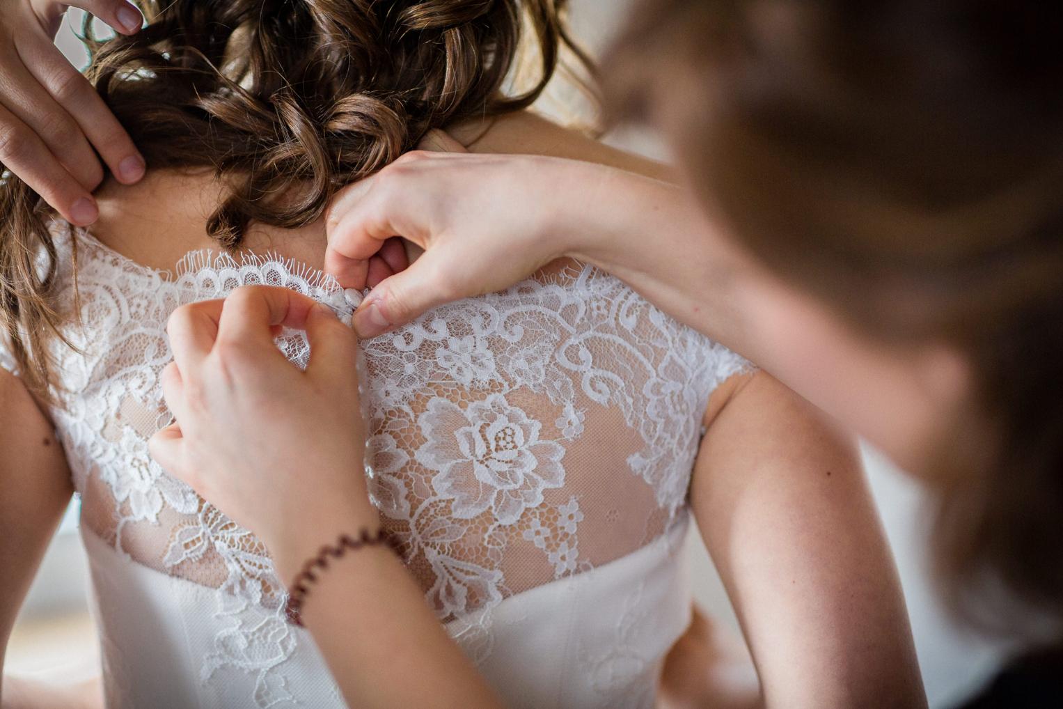 Detail vom Zuknöpfen des Spitzenrückens am Brautkleid