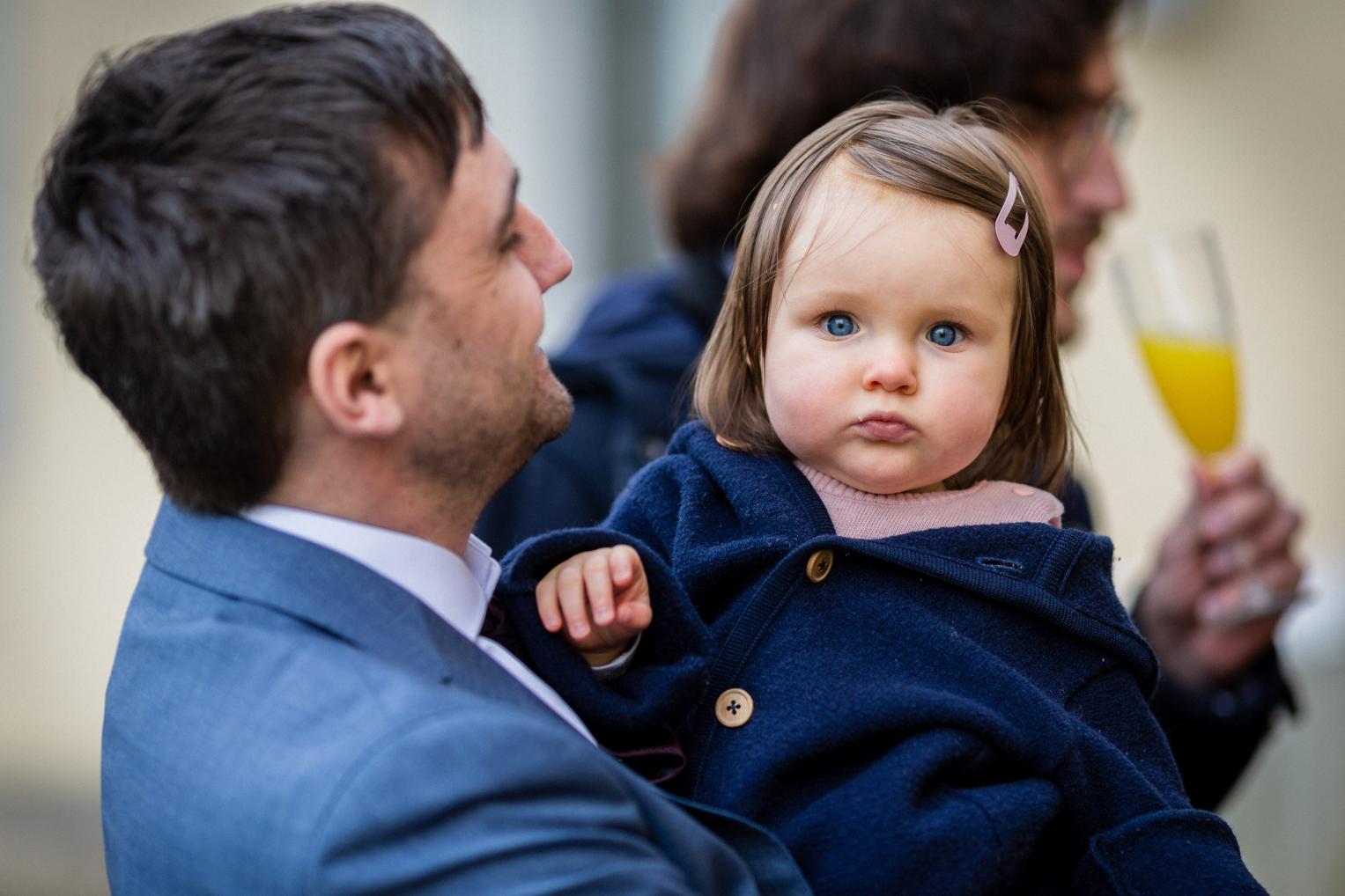 Vater hält seine kleine Tochter mit Sekt beim Empfang