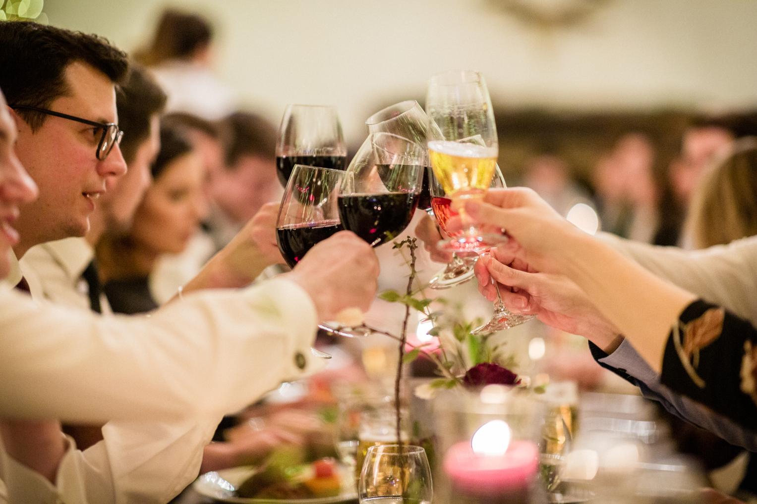 Gäste stoßen mit Wein an der Hochzeitstafel an
