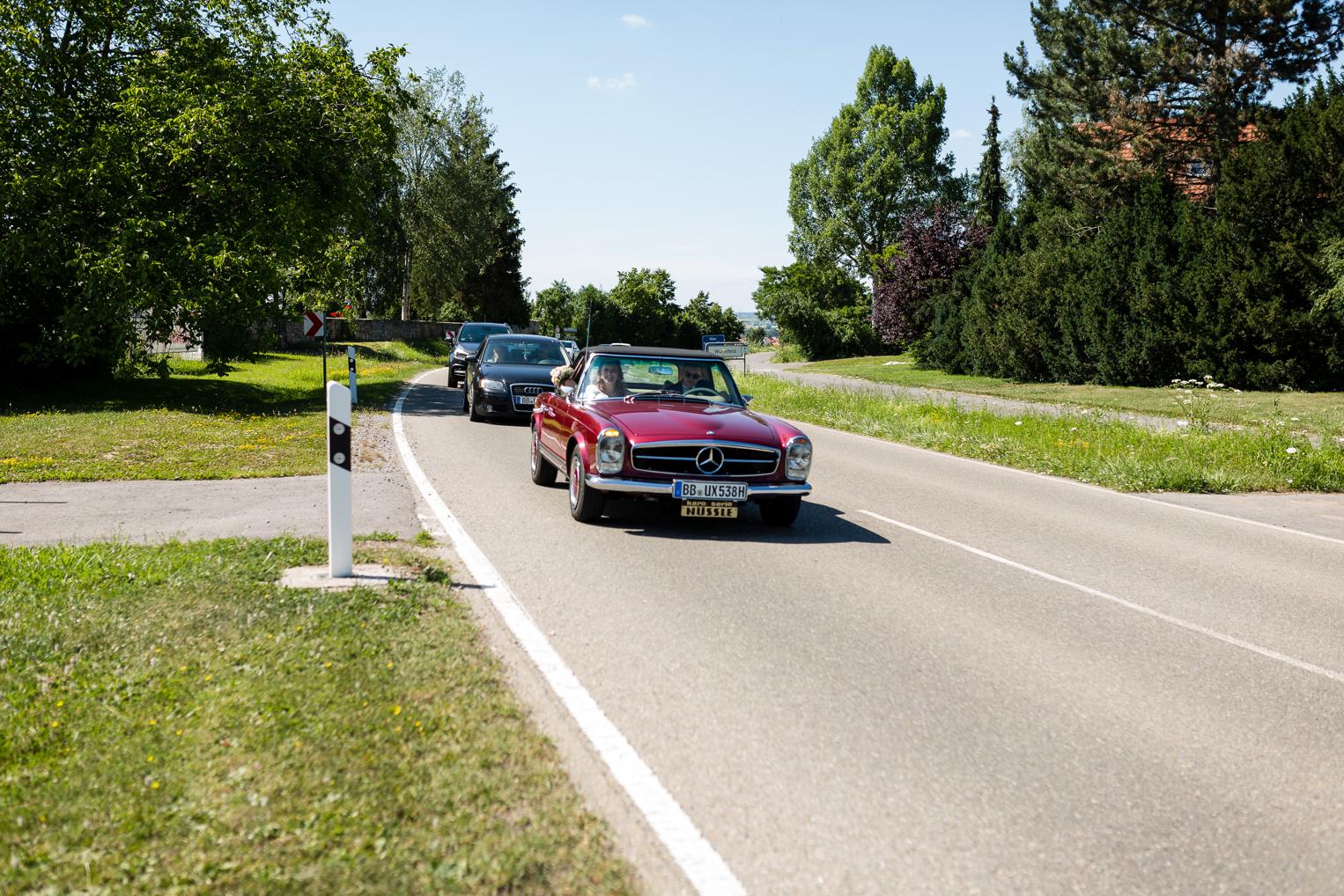Roter Mercedes Oldtimer als Hochzeitsauto fährt zur Hofschuir