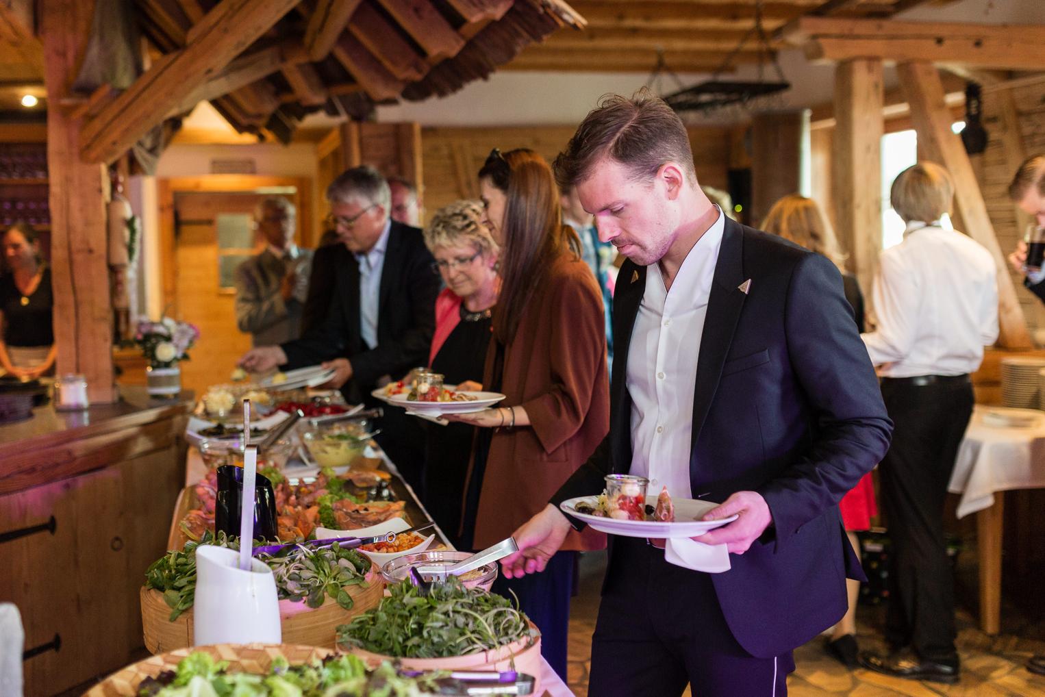Hochzeitsgäste bedienen sich am rustikalen Buffet