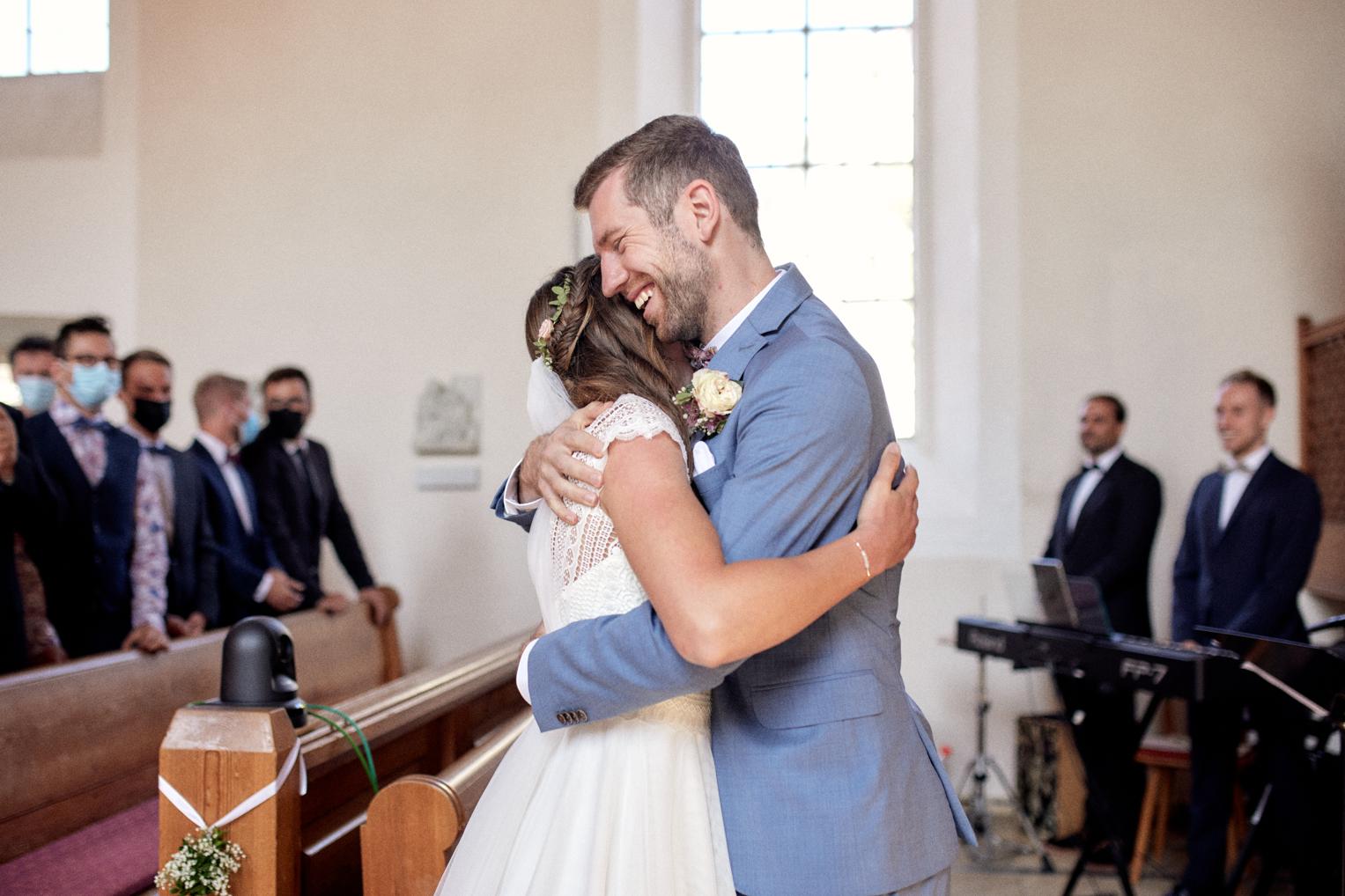 Braut und Bräutigam umarmen sich lachend am Altar