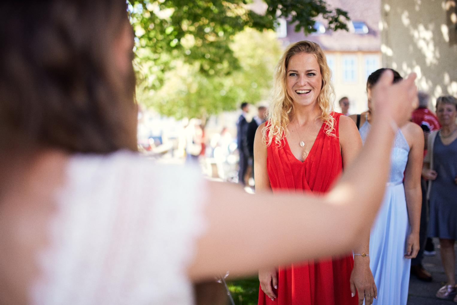Strahlende Hochzeitsgästin im roten Kleid nach der Trauung