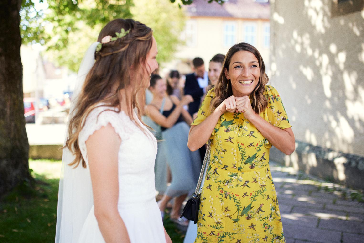Freundin im Sommerkleid gratuliert der Braut lachend