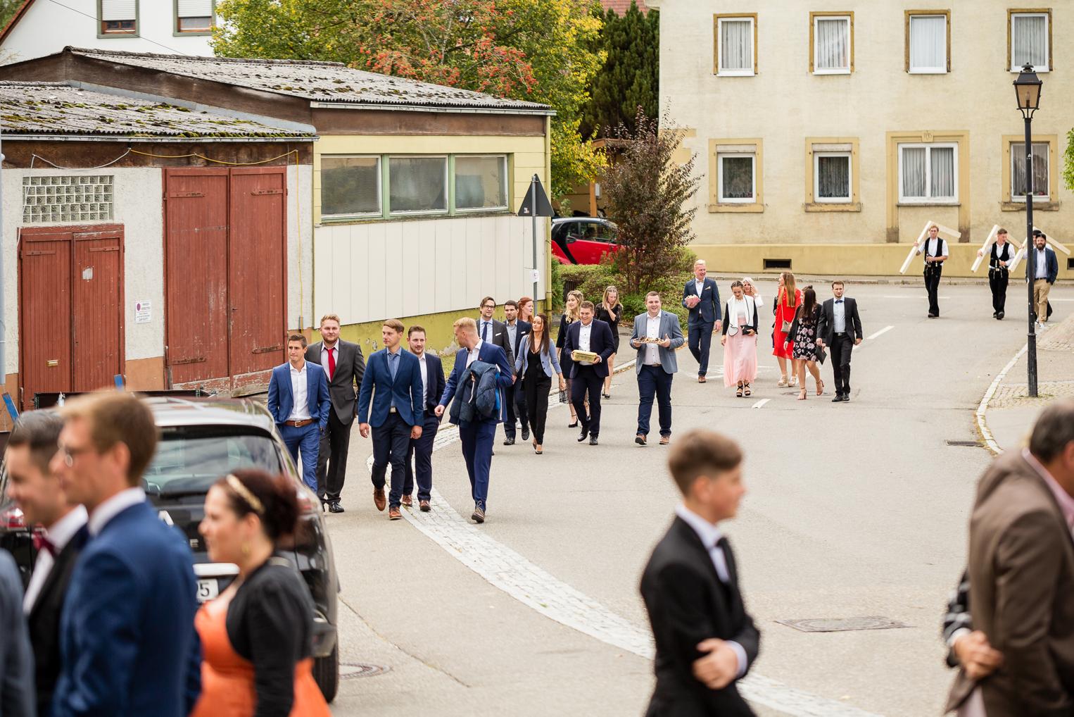 Hochzeitsgäste gehen gemeinsam zur Kirche in Gruol, Hochzeitsreportage St. Clemenskirche