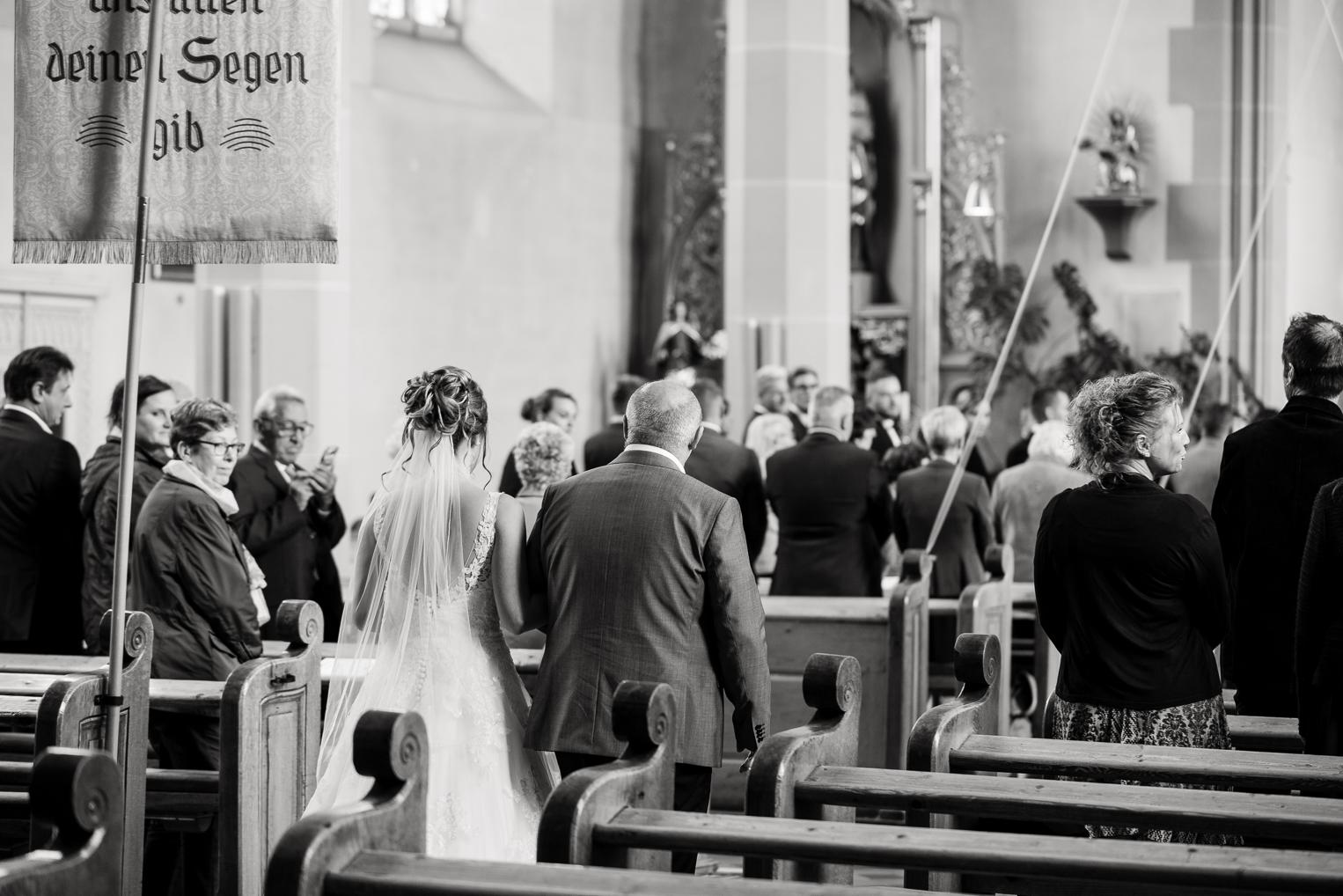 Schwarz-Weiß: Braut zieht in die St. Clemenskirche Gruol ein, begleitet vom Vater