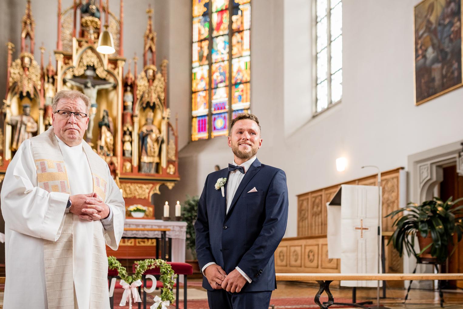Bräutigam wartet am Altar der St. Clemenskirche Gruol neben dem Pfarrer