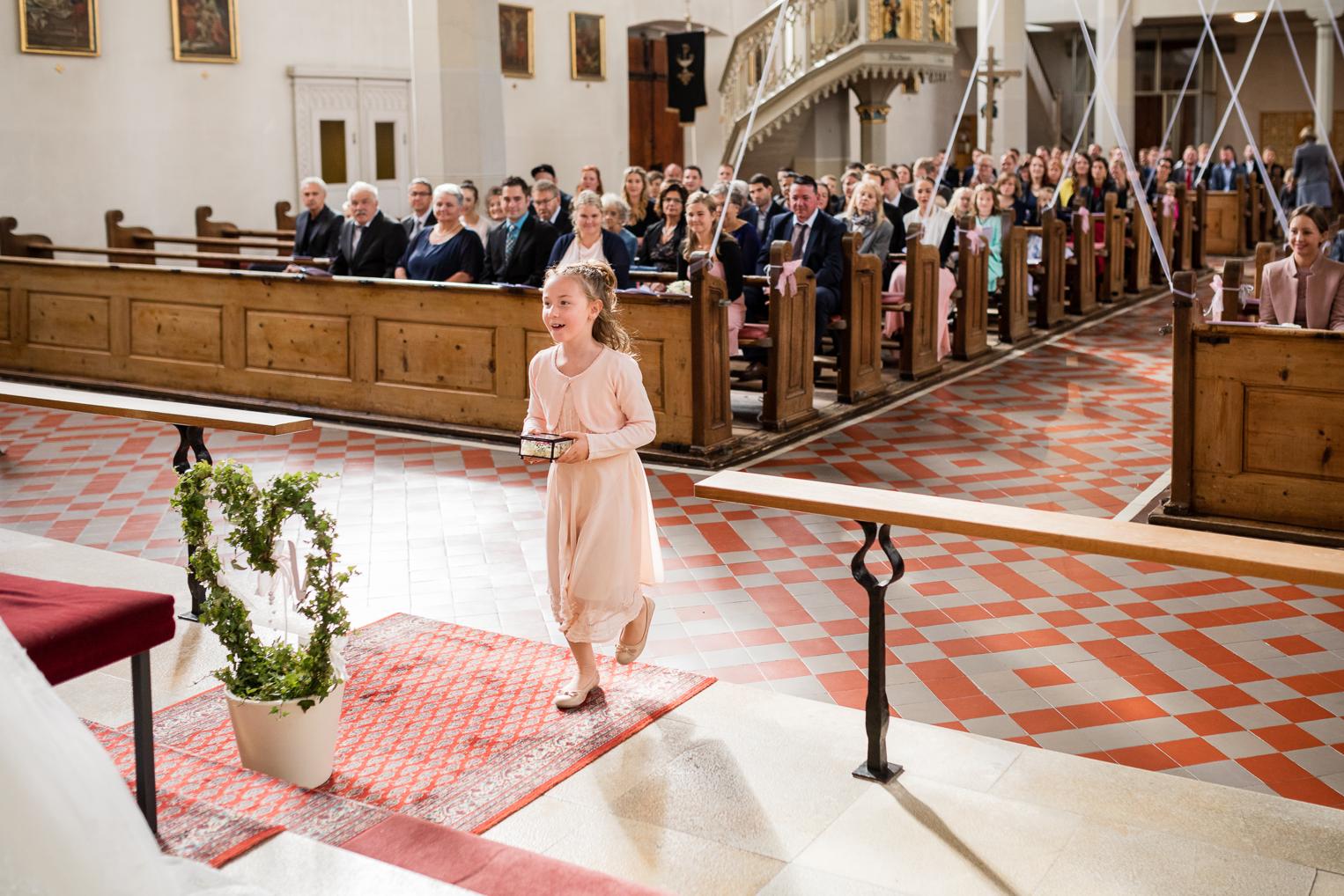 Blumenmädchen trägt Ringkissen zum Altar in der vollbesetzten St. Clemenskirche Gruol