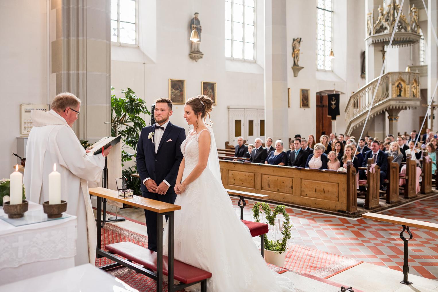 Brautpaar vor dem Pfarrer am Altar der St. Clemenskirche Gruol, Gäste im Hintergrund