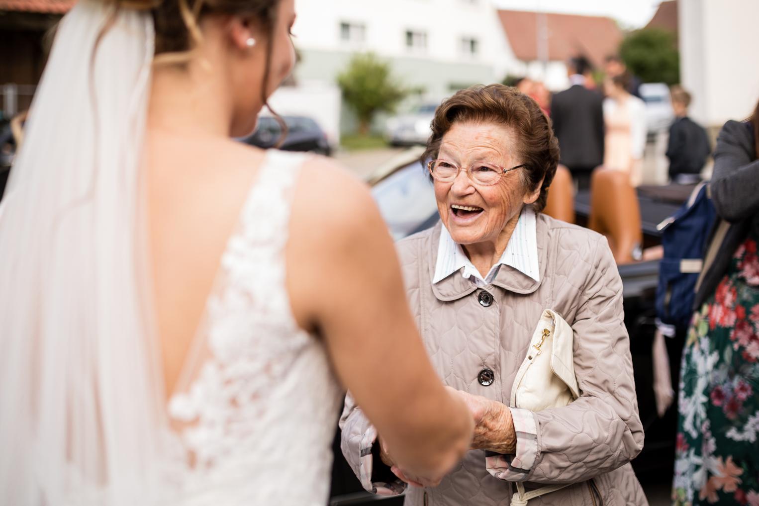 Oma gratuliert der Braut strahlend vor der St. Clemenskirche Gruol nach der Trauung