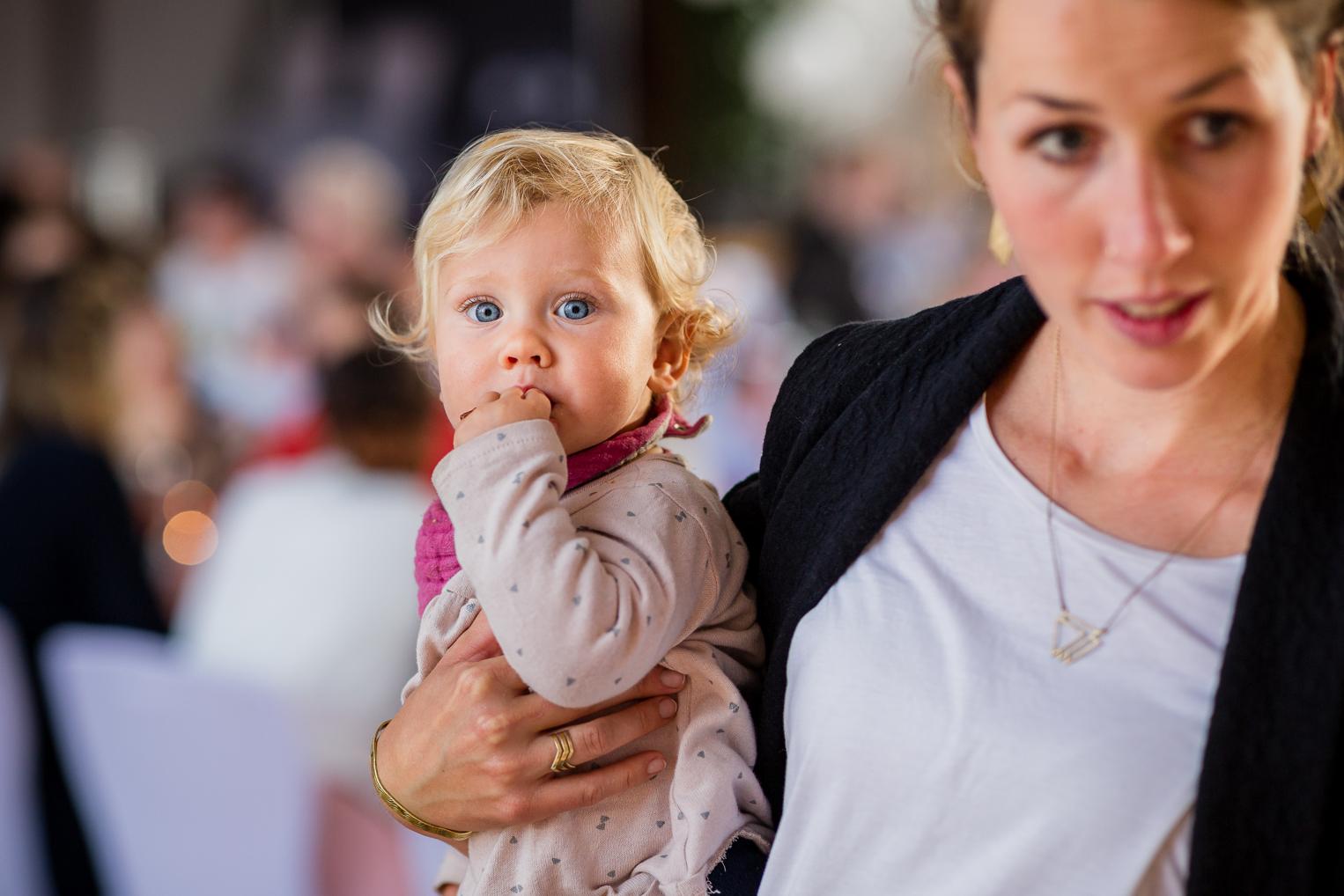 Hochzeitsreportage: Baby mit blauen Augen auf dem Arm der Mutter bei der Hochzeitsfeier