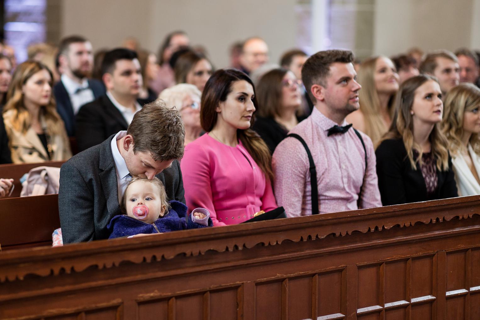 Hochzeitsgäste auf den Bänken der Kirche Gärtringen, Vater mit Baby im Arm