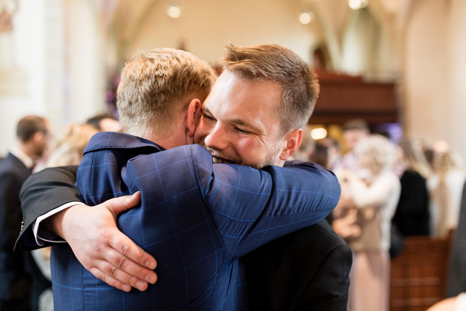 Bräutigam umarmt lachend seinen besten Freund nach der Hochzeit in der Kirche Gärtringen