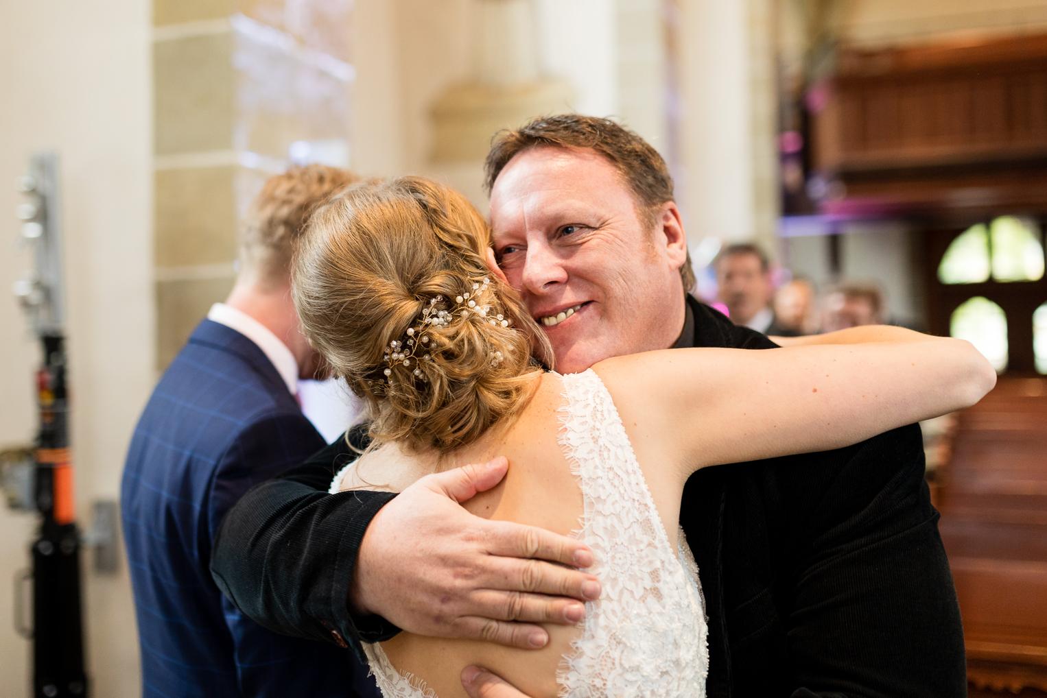 Gast umarmt die Braut strahlend nach der kirchlichen Hochzeit in Gärtringen