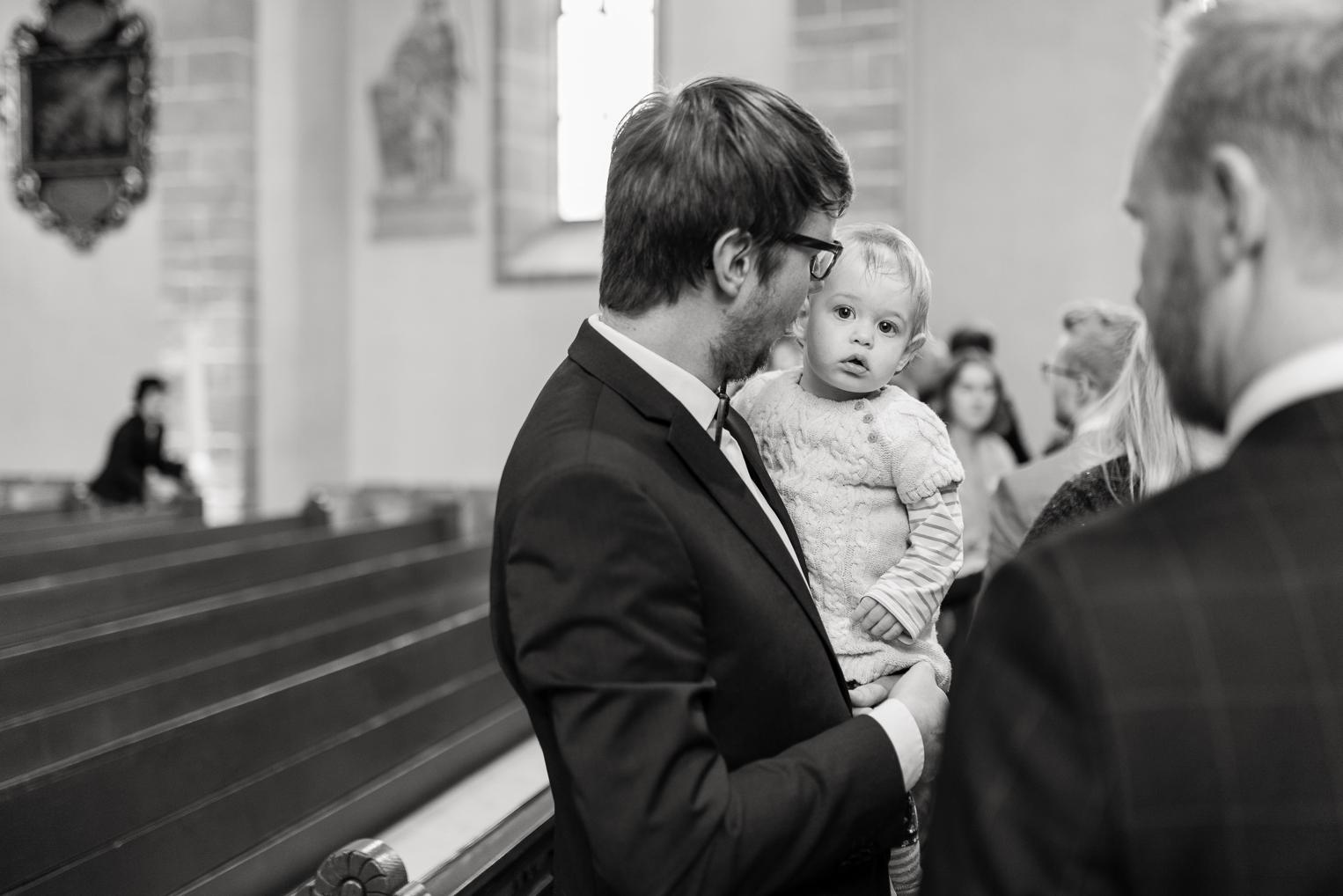 Gast hält Baby auf dem Arm beim Auszug nach der Trauung in der Kirche Gärtringen