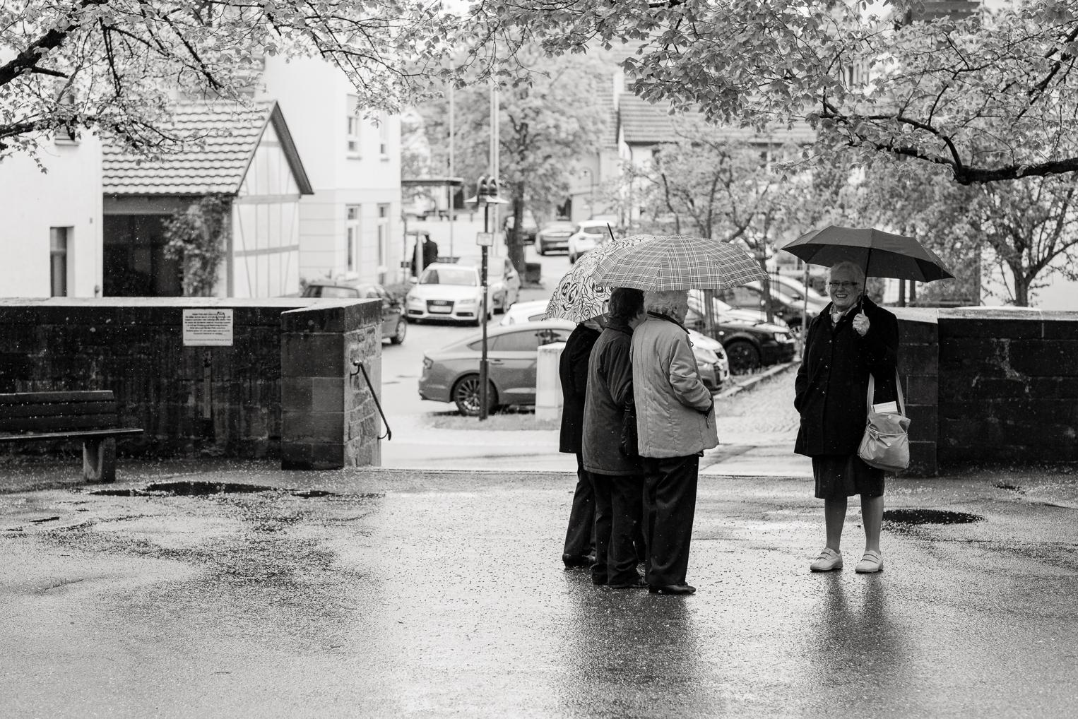 Gäste stehen mit Regenschirmen vor der Kirche Gärtringen nach der Trauung im Regen