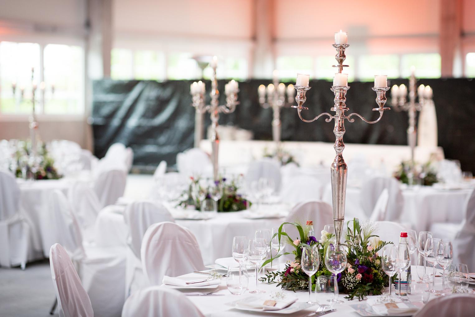 Elegante Hochzeitstafel mit silbernem Kandelaber und Blumengesteck auf weißem Tischtuch