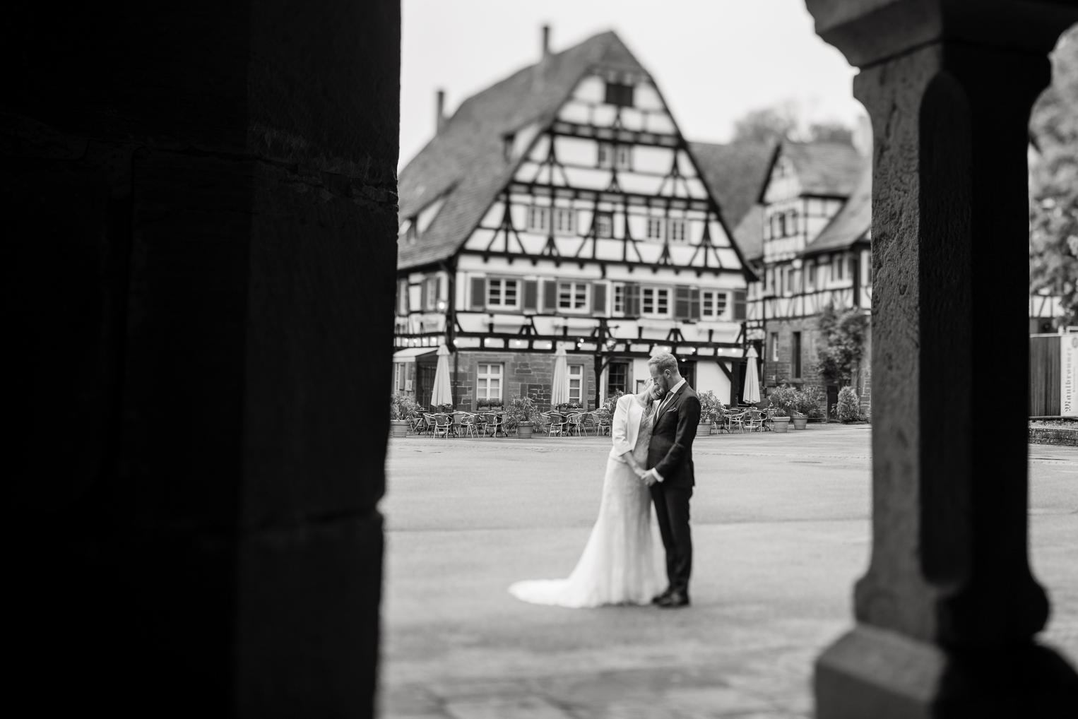 Brautpaar küsst sich auf dem Marktplatz vor dem Kloster Maulbronn, durch Säulen gerahmt