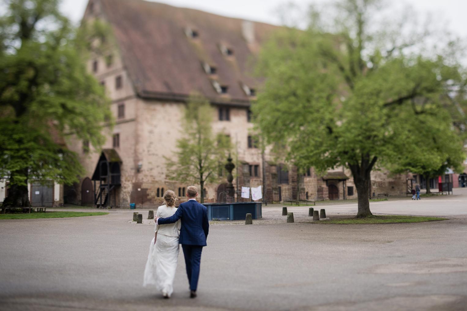 Brautpaar von hinten beim Spaziergang in Richtung Klostergebäude Maulbronn