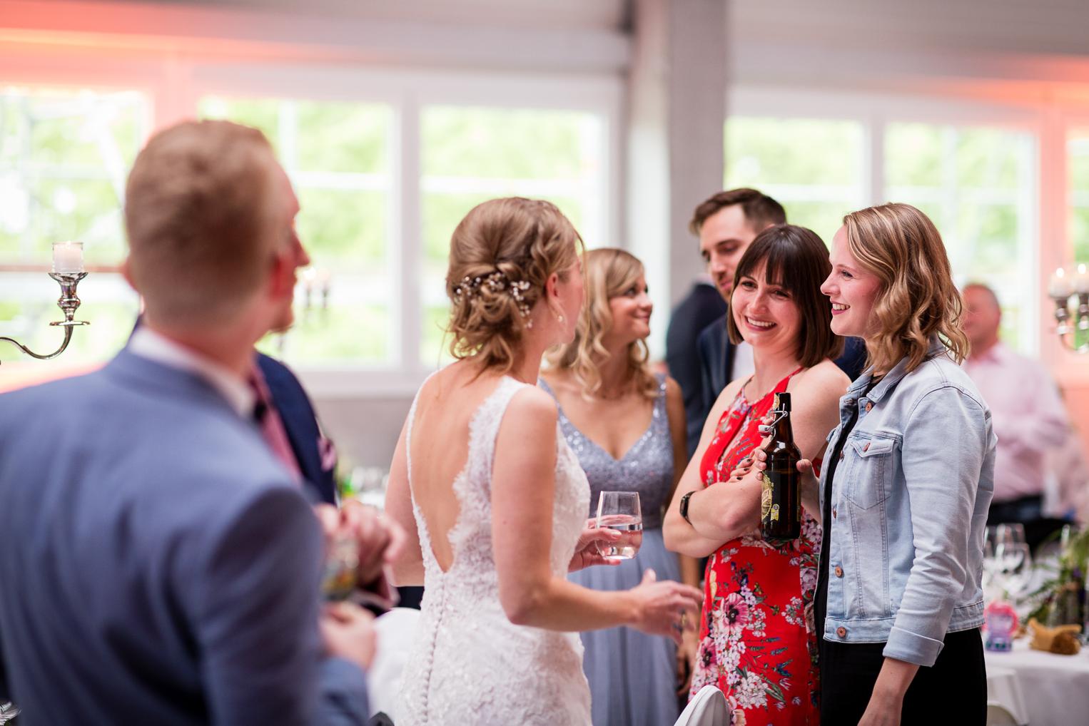 Braut unterhält sich fröhlich mit Gästen beim Empfang nach der Hochzeit