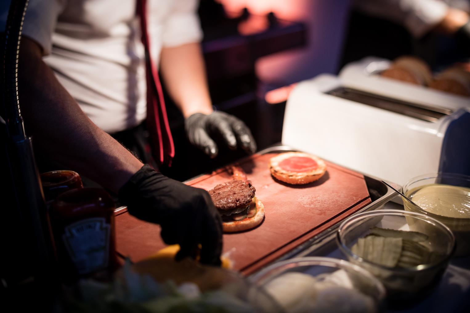 Koch belegt frische Burger für die Hochzeitsgäste beim Catering-Stand