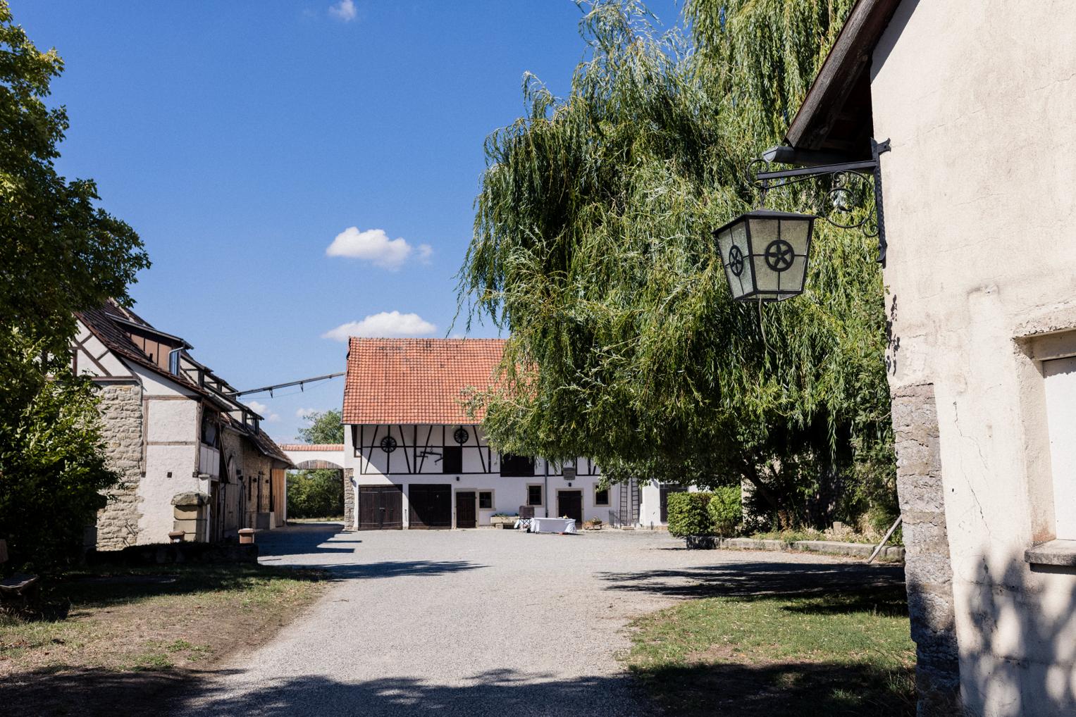 Sonniger Innenhof vom Landgut Halsberg mit großer Trauerweide